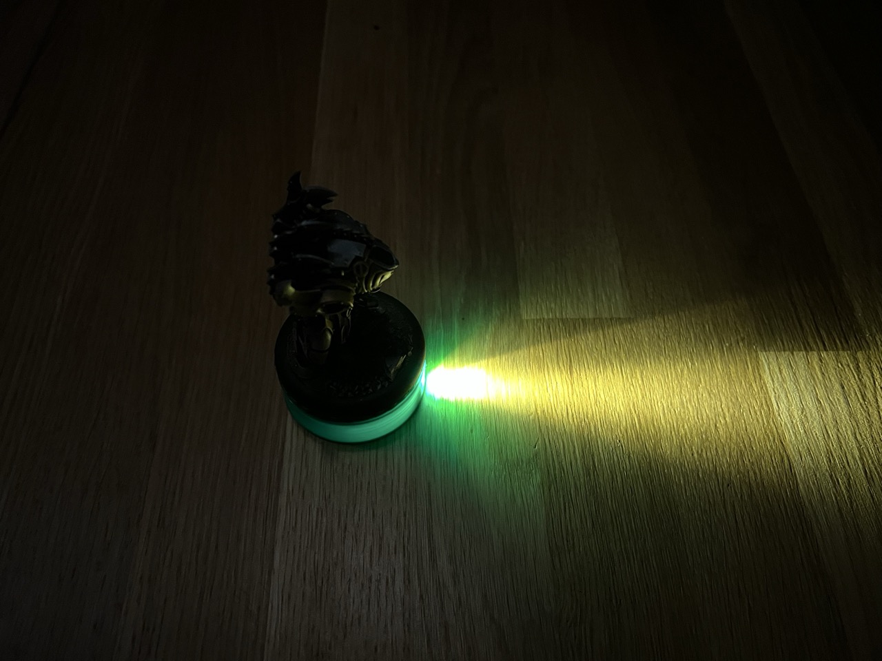 3D printed Beam Base projecting a narrow field of view cone onto a tabletop, with an RPG miniature placed on top.